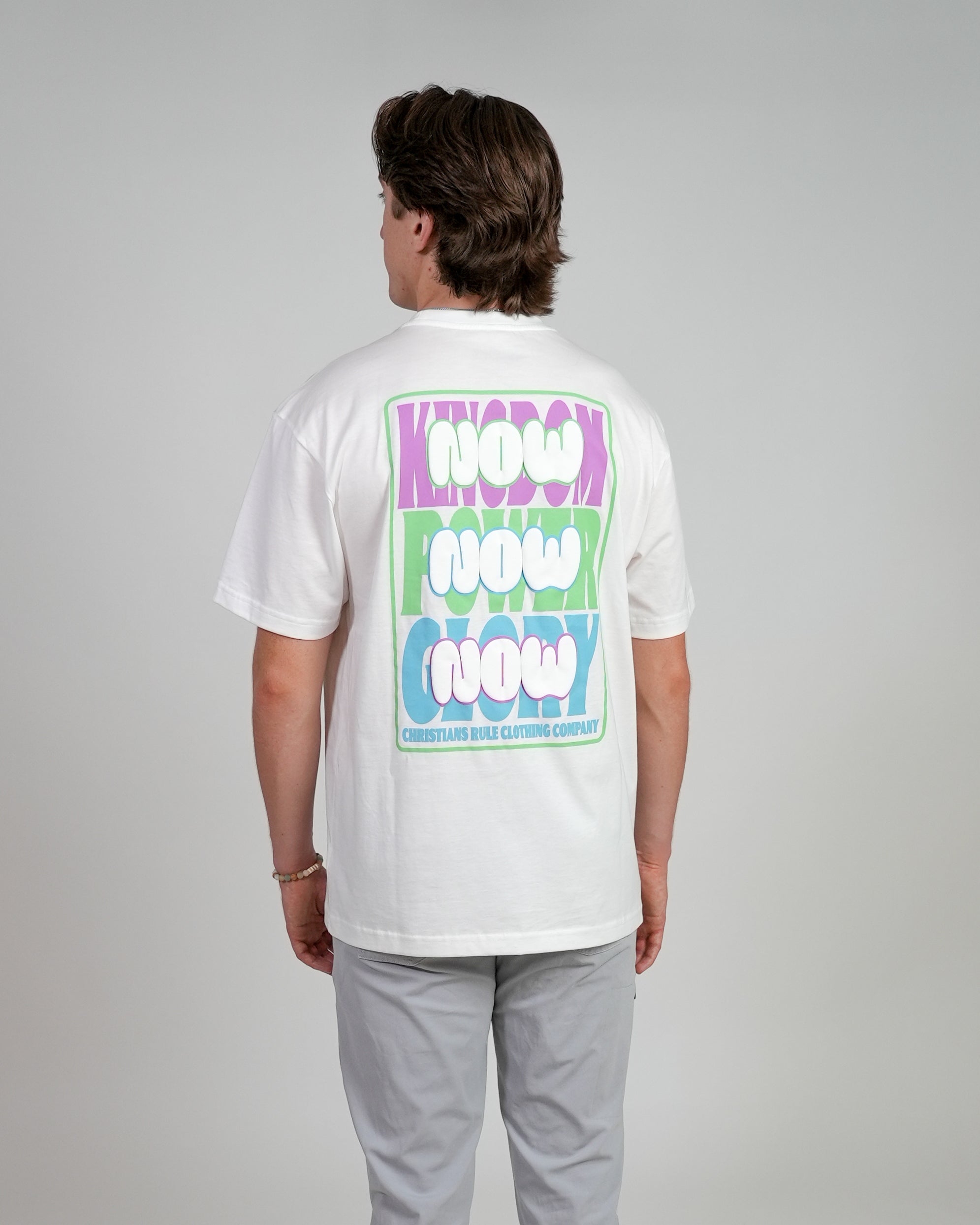 Male model wearing a white Christian t-shirt with colorful text design, standing against a white background.