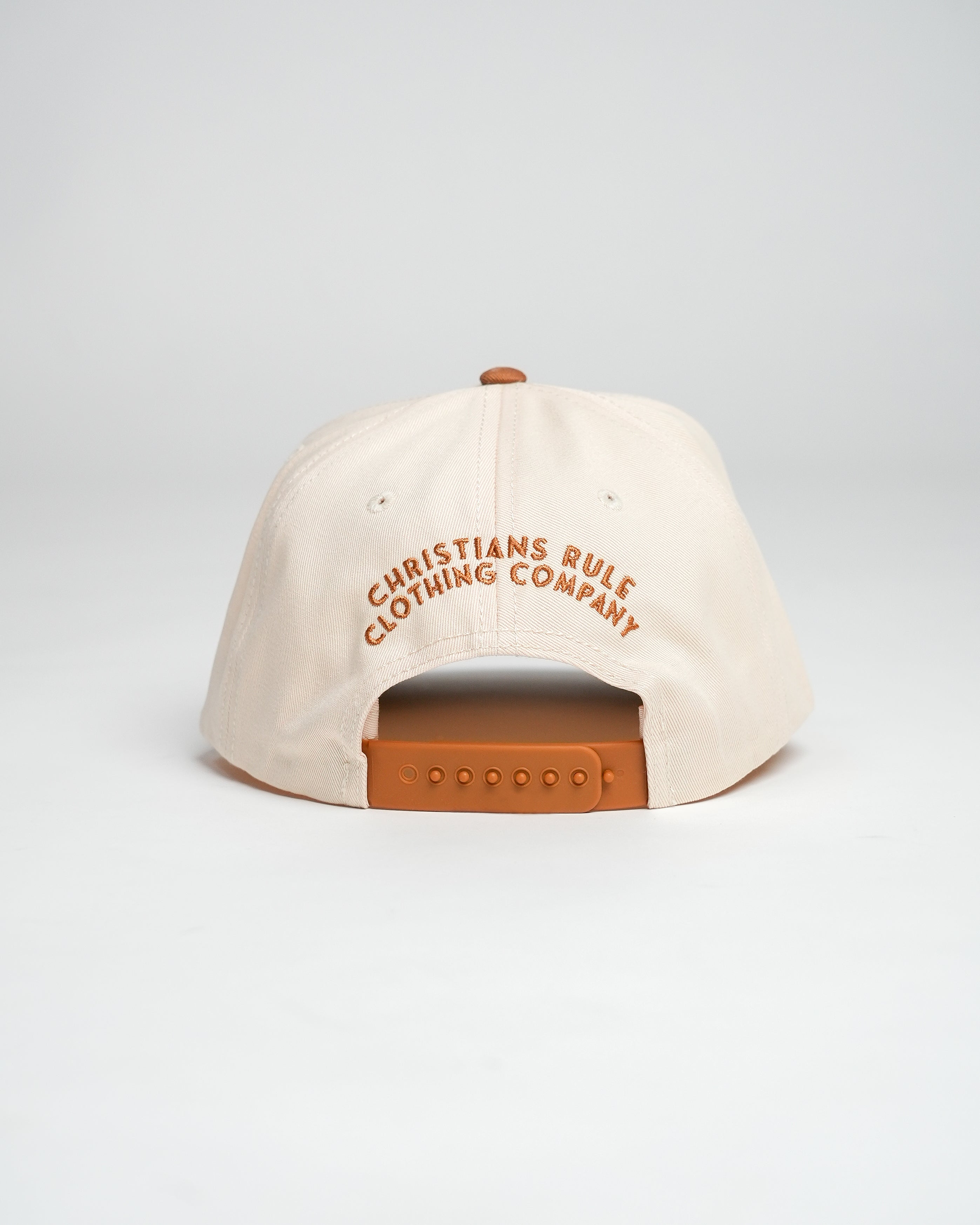 Cream and bronze Christian cap with embroidered text that says 'Christians Rule Clothing Company', against a white background.