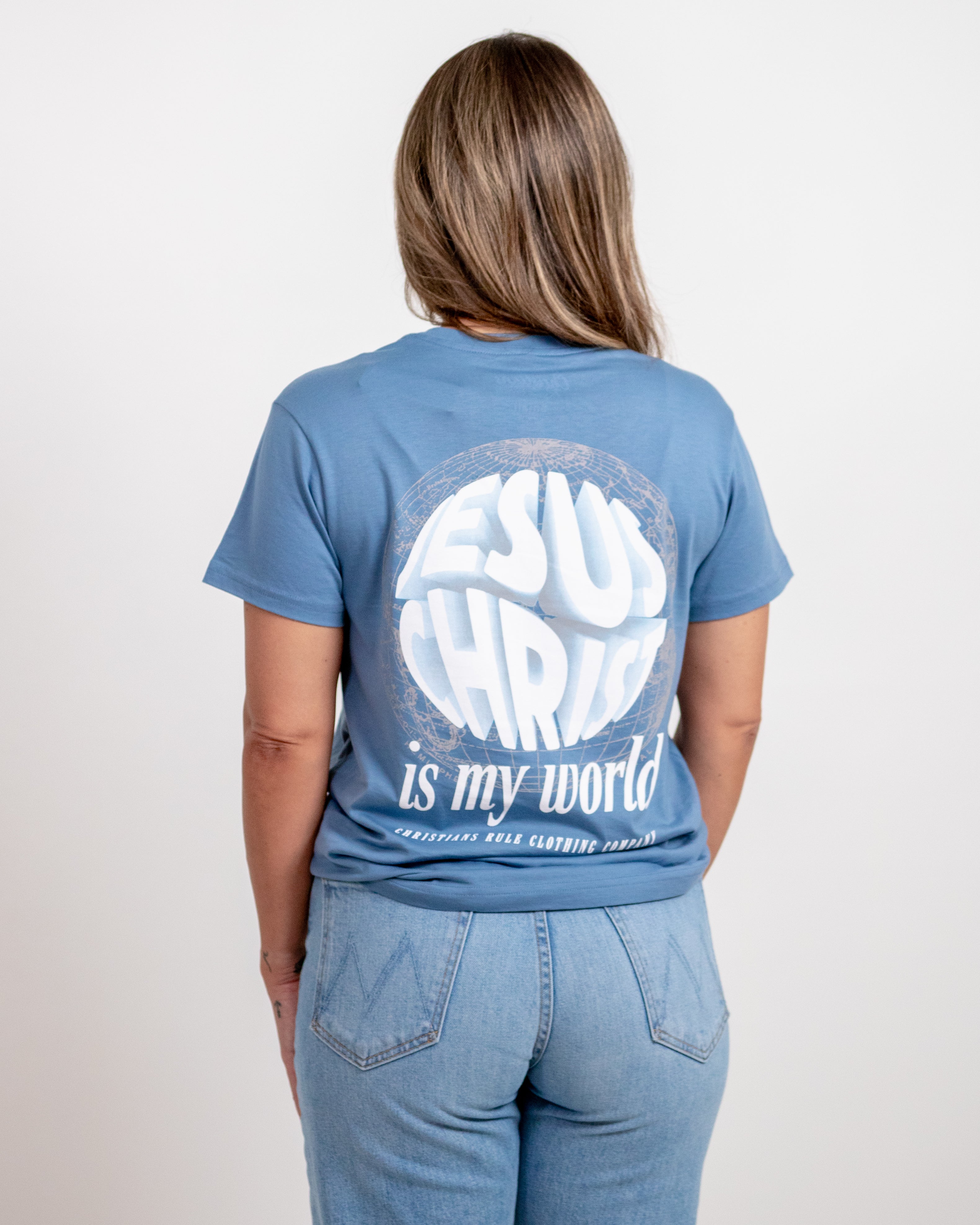 Female model wearing blue Christian t-shirt with a meridian graphic design and bold text saying "Jesus Christ is my world" and "Christians Rule Clothing Company".