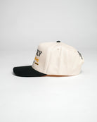 Side view of cream and black Christian cap with embroidered text, against a white background.